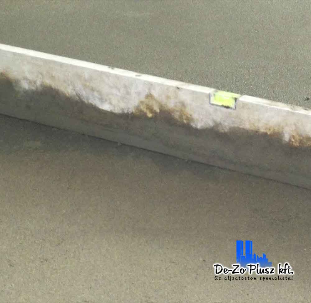 Estrich beton alapozás pontos vízmérték használatával, aljzatbeton kiegyenlítés egy építkezésen. De-Zo Plusz Kft. szakértelmével készített felület