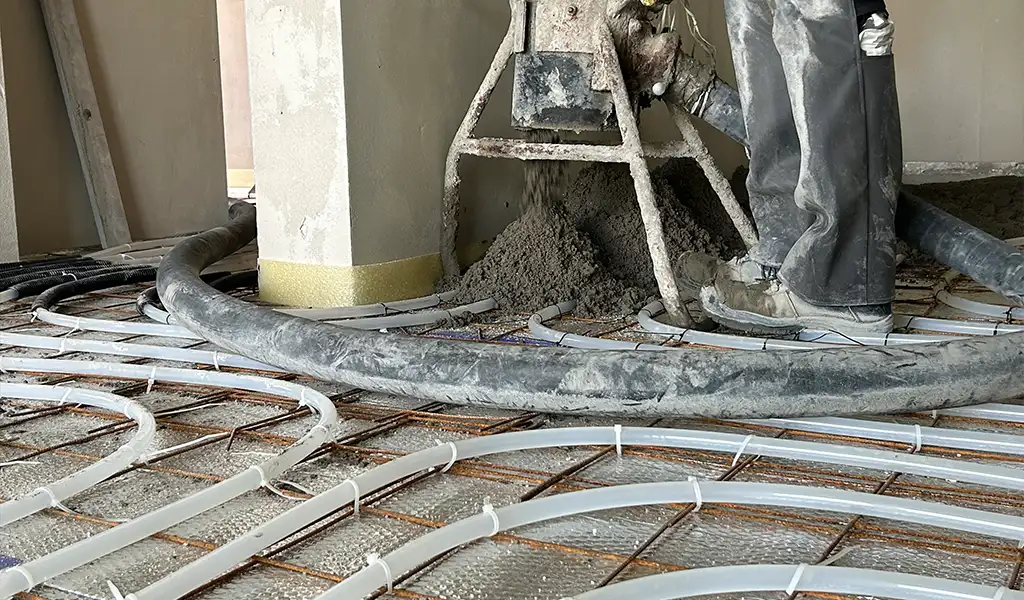 Estrich beton bedolgozása padlófűtés csövezete fölött, amely a kivitelezés folyamatát és a rétegrendet mutatja