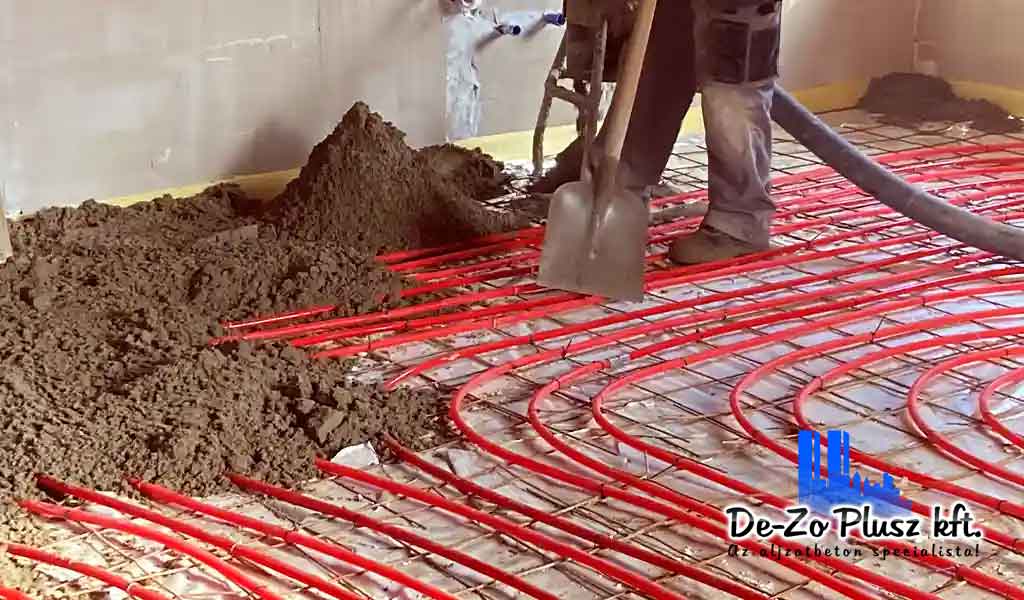 Építési munkálatok során padlófűtés csövekre öntött úsztatott estrich beton, kivitelező szakember lapáttal dolgozik a simításán